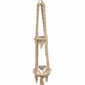May include: A macrame plant hanger in natural beige tones, featuring two circular holders and decorative tassels. The hanger is suspended from a single cord and adorned with small blue beads. This handcrafted piece is designed for displaying plants.