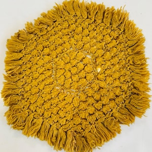 Peut inclure: Tapis rond jaune moutarde noué à la main avec une bordure à franges. Le tapis présente un motif floral et un cercle central ouvert. Le tapis est fait d'un matériau doux et texturé.