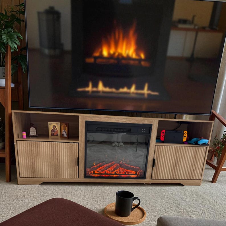 May include: A light oak entertainment center with a built-in electric fireplace, a large TV, and storage. The fireplace has a realistic flame effect. A black mug sits on a small wooden tray.