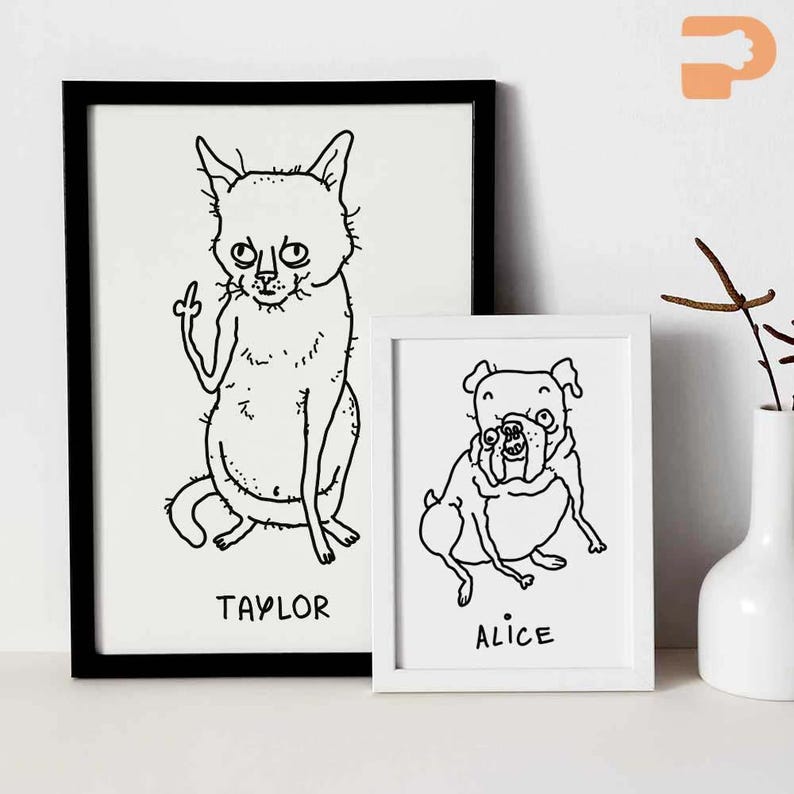 May include: Two framed art prints featuring whimsical black and white illustrations of pets. One print shows a cat giving the middle finger, labeled "TAYLOR." The other depicts a dog, labeled "ALICE."