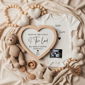 Puede incluir: Anuncio de bebé con un body blanco con la inscripción "Baby Oliver", un marco en forma de corazón con texto, un osito de peluche y patucos. El anuncio incluye una imagen de ultrasonido y elementos decorativos.