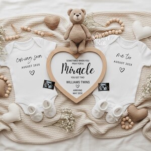 Könnte beinhalten: Eine Babyankündigung mit zwei weißen Baby-Bodys, einem herzförmigen Holzrahmen und einem Teddybären. Auf den Bodys steht "Coming soon" und "Me too" mit dem erwarteten Ankunftsdatum. Der Rahmen zeigt den Text "Sometimes when you pray for a miracle, you get two Williams twins."