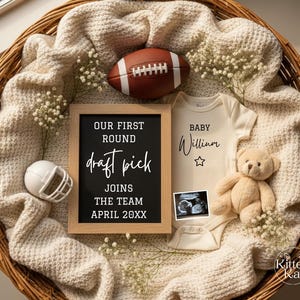 May include: A baby announcement arrangement in a woven basket. It includes a football, a framed sign with text, a white baby onesie, a teddy bear, and a miniature football helmet. The sign reads "OUR FIRST ROUND draft pick JOINS THE TEAM APRIL 20XX."