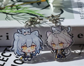 May include: Two acrylic keychains featuring anime-style characters with cat ears and a small cat on their heads. The characters have large eyes and are wearing outfits with black and gold accents. Each keychain has a silver clasp.