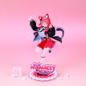 Könnte beinhalten: Klare Acrylfigur einer Figur mit rosa Haaren, Katzenohren und Brille, die eine schwarze Jacke und einen roten Rock trägt. Die Figur steht auf einem rosa Sockel mit dem Namen "NANALLY" und Pfotenabdrücken.