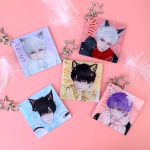 May include: Five square keychains with anime-style illustrations of male characters with cat ears. Each keychain has a different character name: Xavier, Sylus, Caleb, Zayik, and Harvey. The keychains are attached to star-shaped metal clasps.