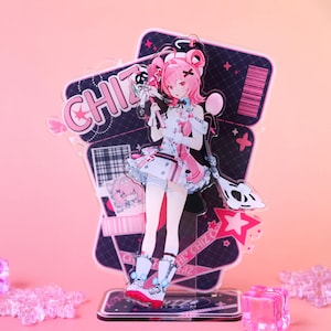 Puede incluir: Un expositor de acrílico con un personaje de estilo anime de pelo rosa, que lleva un conjunto blanco y rosa con estética de enfermera. El personaje sostiene un bastón médico. El panel de fondo muestra el texto CHIZ y un código de barras.