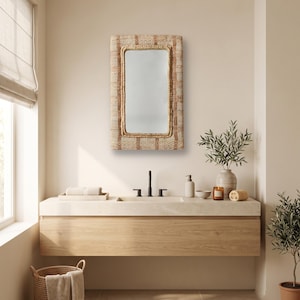 May include: A rectangular wall mirror featuring a textured, woven frame in shades of tan and beige. The mirror has a smooth, reflective glass surface and a thick, braided border that surrounds the central glass pane, mounted on a wall.