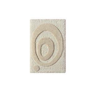 May include: Rectangular beige bath mat with a raised, abstract design of concentric circles in a lighter beige hue. A small, circular accent is positioned below the circles. The mat has a textured surface.