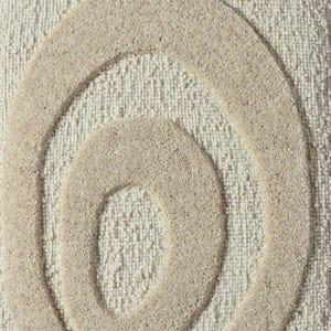 May include: Close-up of a beige rug with a textured surface. The rug features a raised, abstract design of concentric ovals in a lighter beige color. The design adds a modern touch to the neutral-toned rug.
