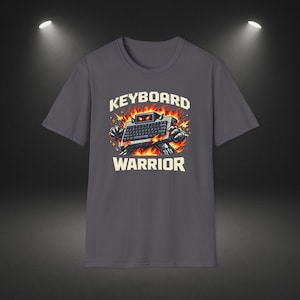 Op de afbeelding: Donkergrijs t-shirt met een afbeelding van een toetsenbordrobot met vlammen en de witte tekst "KEYBOARD WARRIOR". De robot heeft een toetsenbord als lichaam. Het shirt heeft een ronde hals.