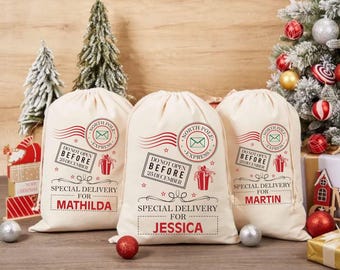 May include: Three cream-colored Christmas gift bags with red and green graphic designs. Each bag has the text "North Pole Express" and "Do Not Open Before 25 December". The bags are labeled "Special Delivery For" with names.