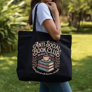 May include: Black tote bag with the text "Anti Social Book Club Member Only" in a decorative font. The design includes a stack of books, a coffee cup, and the phrase "Making friends with characters, not people."