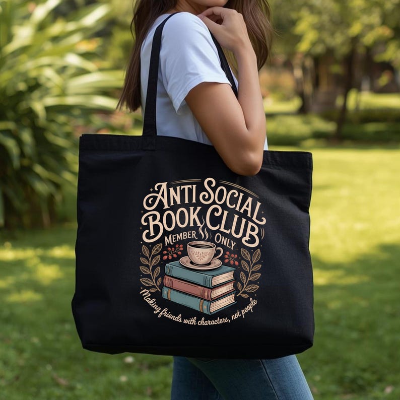 May include: Black tote bag with the text "Anti Social Book Club Member Only" in a decorative font. The design includes a stack of books, a coffee cup, and the phrase "Making friends with characters, not people."