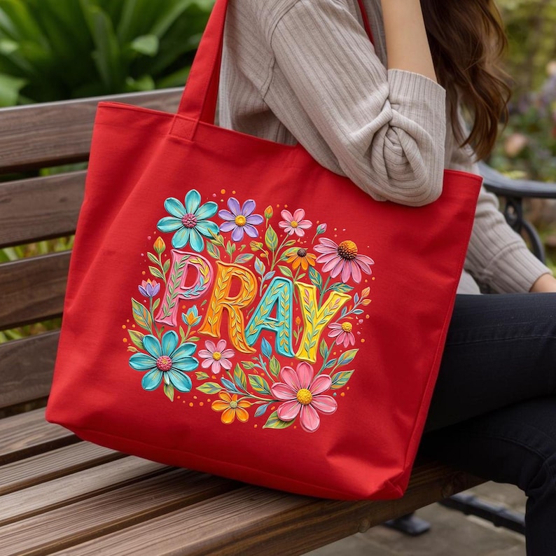 May include: A red tote bag with a floral design and the word "PRAY" in colorful letters. The flowers are in shades of blue, pink, yellow, and orange, with green leaves. The bag has two handles.