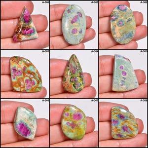 May include: Nine polished gemstones in various shapes. The stones feature a mix of pink, green, brown, and blue hues. Each stone has a unique pattern and texture, with visible inclusions and colour variations. The gemstones are displayed against a neutral background.