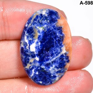May include: Oval-shaped sodalite gemstone with a striking blend of deep blue, white, and orange hues. The stone's surface displays intricate veining and patterns, creating a unique and natural aesthetic. The text "A-598" is visible in the upper right corner.