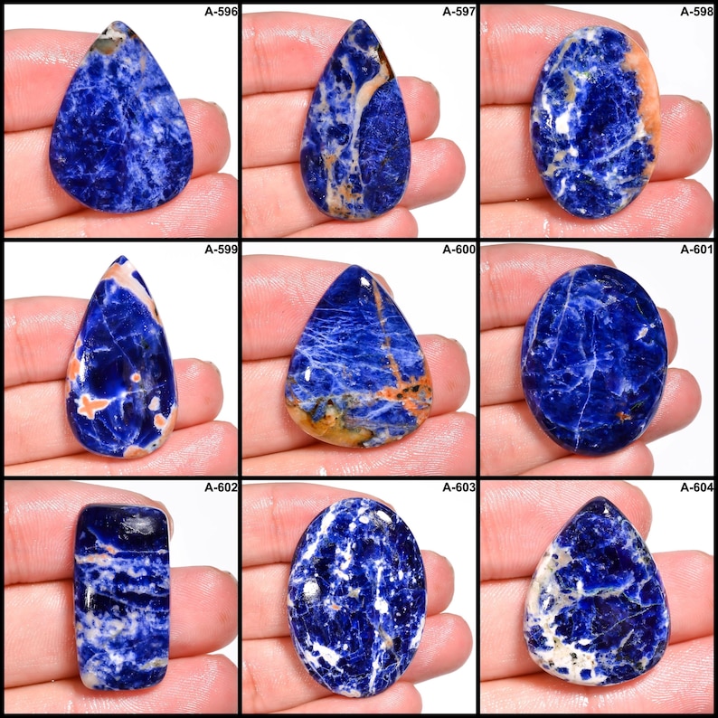 May include: A collection of nine sodalite gemstones in various shapes, including teardrop and oval. The stones feature a deep blue color with white and orange veining. Each stone is unique, with variations in pattern and color.
