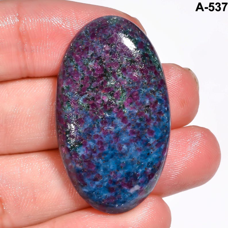 Pode incluir: Uma pedra preciosa oval com um gradiente de cores vibrante. A parte superior apresenta um tom roxo profundo, que transita para uma mistura salpicada de roxo e verde, e finalmente se mistura em um azul rico na base. O texto "A-537" est&aacute; no canto superior direito.