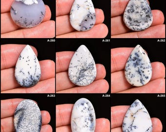 May include: A collection of nine polished gemstones, each with a unique pattern. The stones are primarily white with intricate black and gray dendritic inclusions. Shapes vary from round to teardrop and oval. Each stone is labeled with a number.