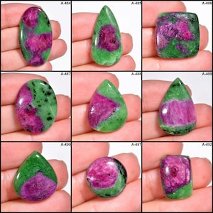 Peut inclure: Neuf pierres précieuses polies de formes variées. Chaque pierre présente un centre magenta vif entouré d'une bordure verte. Les pierres sont présentées sur un fond neutre, mettant en valeur leurs couleurs et textures. Les pierres sont étiquetées A-484 à A-492.