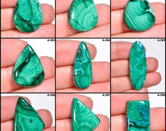 Puede incluir: Nueve piedras preciosas de malaquita pulidas en varias formas, incluyendo lágrima, ovalada y rectangular. Las piedras muestran un color verde vibrante con patrones arremolinados y vetas verde oscuro. Cada piedra se sostiene en una mano.