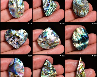 May include: A collection of iridescent abalone shell cabochons in various shapes, including oval, triangular, heart, and teardrop. The shells display a range of colors, such as blue, green, and purple, with a shimmering, pearlescent effect. Each cabochon is unique.