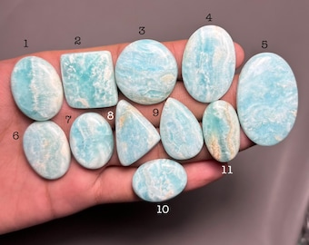 May include: Eleven Amazonite gemstones in various shapes, including oval, rectangular, and teardrop. The stones are a light blue-green colour with white veining. The gemstones are numbered 1 to 11.