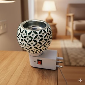 Könnte beinhalten: Dekorativer ätherischer Öl Diffusor in Weiß und Grün mit floralem Muster. Der Diffusor hat eine silberne Schale und eine weiße Steckbasis mit einem roten Ein-/Ausschalter. Er steht auf einer Holzoberfläche.