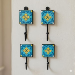 May include: Four decorative wall hooks with square, patterned tiles in turquoise, yellow, and white. Each hook has a black metal frame and a curved hook. The hooks are mounted on a white wall.