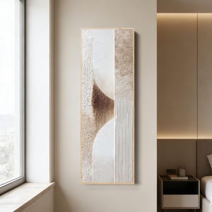 Può includere: Opera d'arte astratta da parete in una cornice rettangolare verticale. L'opera presenta un design strutturato con una tavolozza di bianco, beige e marrone. Il design include elementi curvi e lineari, creando un'estetica moderna e minimalista.