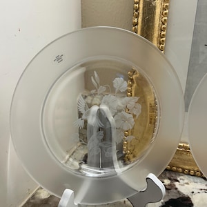 May include: A clear glass plate with a frosted rim and a central etched design featuring a hummingbird hovering near a cluster of flowers. The plate includes a small printed label that reads "OVER 24% FULL LEAD CRYSTAL 8 INCH".