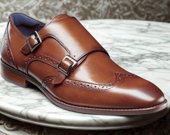 Sapatos sociais masculinos de couro marrom com fivela dupla: modelo brogue com bico wingtip.