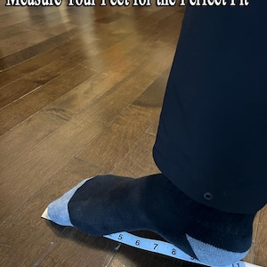 May include: A foot wearing a black sock with a gray toe and heel is being measured with a ruler. The ruler shows measurements in inches. The text "Measure Your Feet for the Perfect Fit" is at the top of the image.
