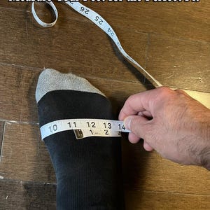 Puede incluir: Un pie con un calcet&iacute;n negro se mide con una cinta m&eacute;trica blanca. La cinta m&eacute;trica lee de 25,4 a 35,6 cm. El texto "Measure Your Feet for the Perfect Fit" est&aacute; en la parte superior de la imagen.