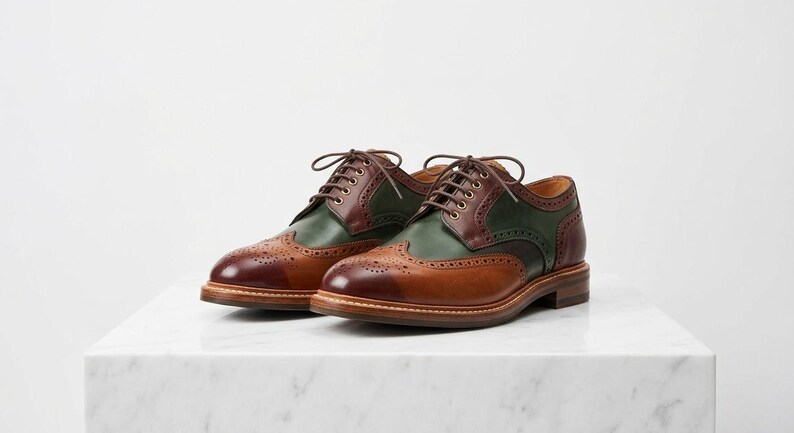 May include: A pair of lace-up oxford shoes featuring a wingtip design with decorative brogue perforations. The shoes are constructed with a combination of tan, dark brown, and forest green leather panels, finished with brown laces and a stacked heel.