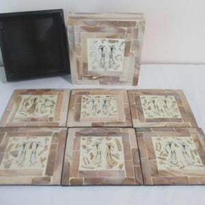May include: A set of decorative coasters and a box. The coasters and box are made of small, rectangular tiles in shades of beige and brown. Each coaster features a central square with a stylized figure design.