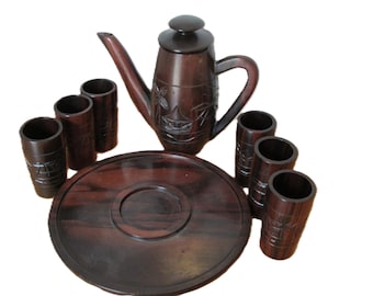 May include: A dark brown wooden tea set with a teapot, six cups, and a tray. The teapot and cups have intricate carvings.