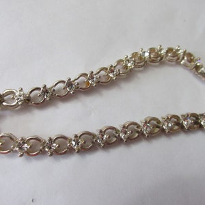 May include: A silver bracelet with a delicate chain design and clear cubic zirconia stones.