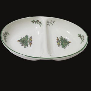 May include: A white divided serving dish with a green rim and a Christmas tree design. The dish is oval shaped and has two sections.