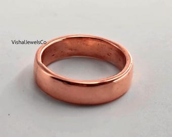 May include: A copper-colored ring with a smooth, polished surface. The ring is a simple band design, with a rounded profile. The text "VishalJewelsCo" is visible on the upper left side of the image.