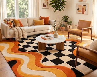 May include: A large area rug featuring a bold design that combines a black and white checkered pattern on one side with flowing, wavy bands of orange, yellow, and cream colors on the other side, creating a striking contrast in the floor covering.