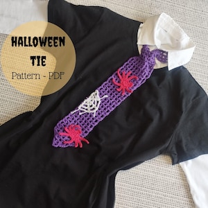 May include: A purple crochet Halloween tie with spider and web accents, displayed on a black shirt with a white collared undershirt. The tie features red spiders and a white web design. Text on the image reads "Halloween Tie Pattern - PDF."