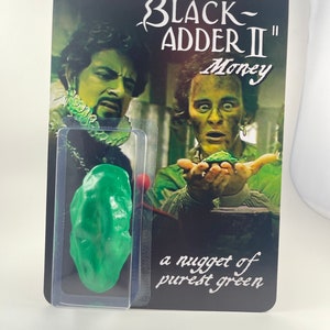 May include: A Black Adder II Money card with a green nugget of purest green. The card features a picture of two men from the show, one holding the green nugget.
