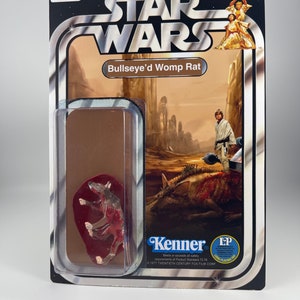 May include: A vintage Star Wars action figure of a brown and red Womp Rat, called Bullseye'd Womp Rat, in a plastic blister pack. The figure is from the Kenner toy line and has the Star Wars logo and the words "Ages 4 and up" on the packaging.