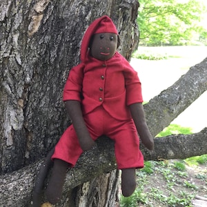 May include: A plush monkey toy wearing a red sleepwear outfit with a matching hat. The monkey is sitting on a tree branch.