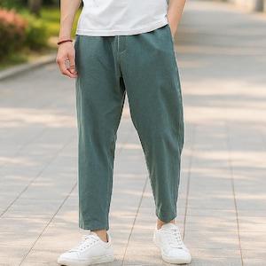 Puede incluir: Pantalones casuales verdes con un corte holgado, combinados con zapatillas blancas. Los pantalones tienen un diseño sencillo y un aspecto cómodo. El conjunto es adecuado para el uso diario.