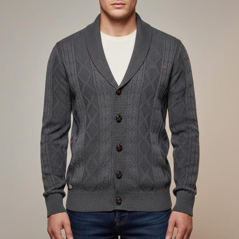 K&ouml;nnte beinhalten: Ein anthrazitfarbener Cardigan mit Schalkragen und Rautenmuster. Der Strickjacke hat eine Knopfleiste mit dunkelbraunen Kn&ouml;pfen und gerippten B&uuml;ndchen. Das Model tr&auml;gt ein wei&szlig;es T-Shirt und blaue Jeans. Ein vielseitiges Kleidungsst&uuml;ck.