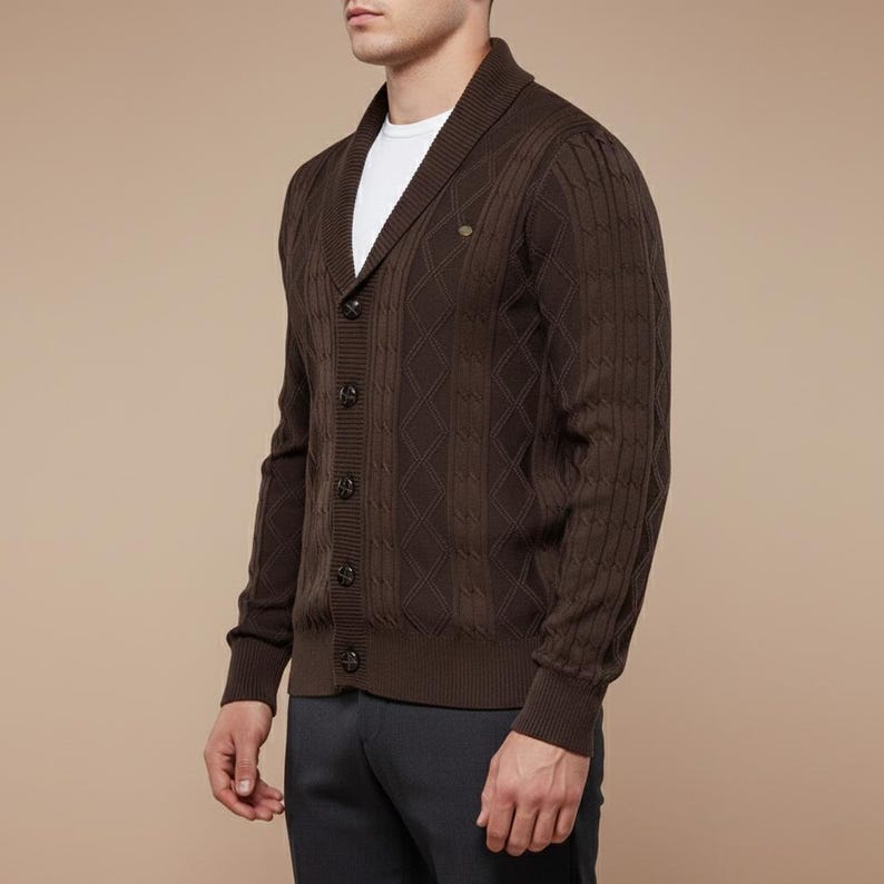 K&ouml;nnte beinhalten: Dunkelbraune Strickjacke mit Zopfmuster, Schalkragen und Knopfverschluss. Der Pullover hat ein Rautenmuster und ein kleines, rundes Knopfdetail auf der Brust. Das Model tr&auml;gt ein wei&szlig;es T-Shirt darunter.