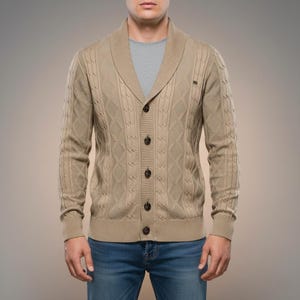 K&ouml;nnte beinhalten: Beigefarbene Strickjacke mit Schalkragen und Knopfleiste. Der Cardigan hat ein Rautenmuster und gerippte B&uuml;ndchen. Die Person tr&auml;gt ein graues T-Shirt und blaue Jeans.